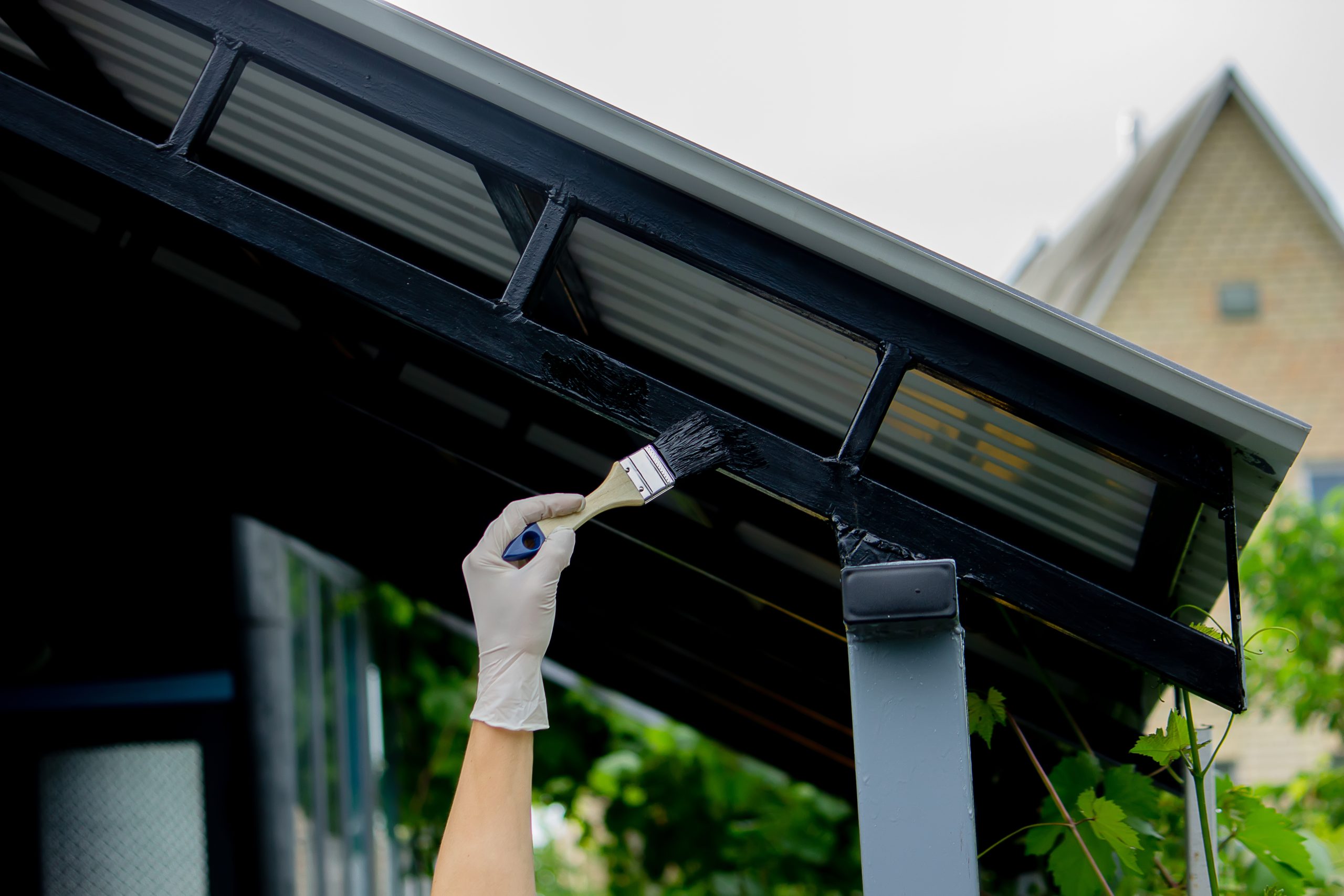 girl paint with a brush black metal. paints the roof. Selective focus