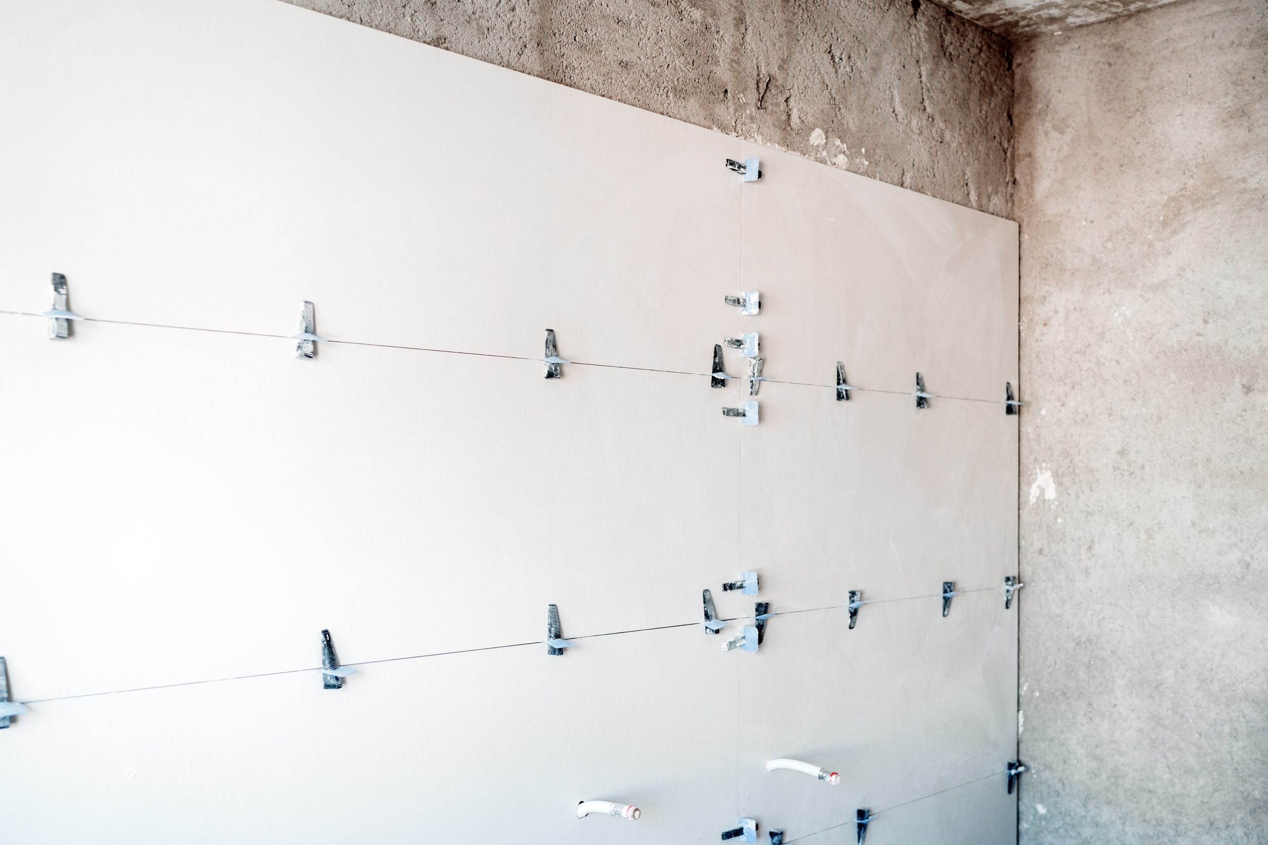 construction site. white modern tiles on bathroom with separator and leveling during works. Home renovation
